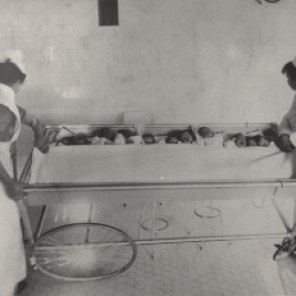 Nursery on Maternity Floor, Winnipeg General Hospital, babies in trolley being taken to their mothers for feeding, ca. 1914. HSC Archives/Museum 999.4.18
