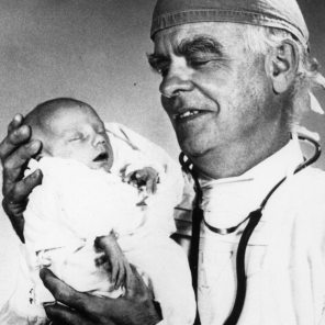 Rh lab, Dr. Jack Bowman Medical Director of Rh Lab, hold the evidence of another successful Rh treatment, a healthy newborn baby, 1960s. HSC Archives/Museum